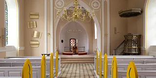 Buet murstensindgang til klostergård med potteplanter.