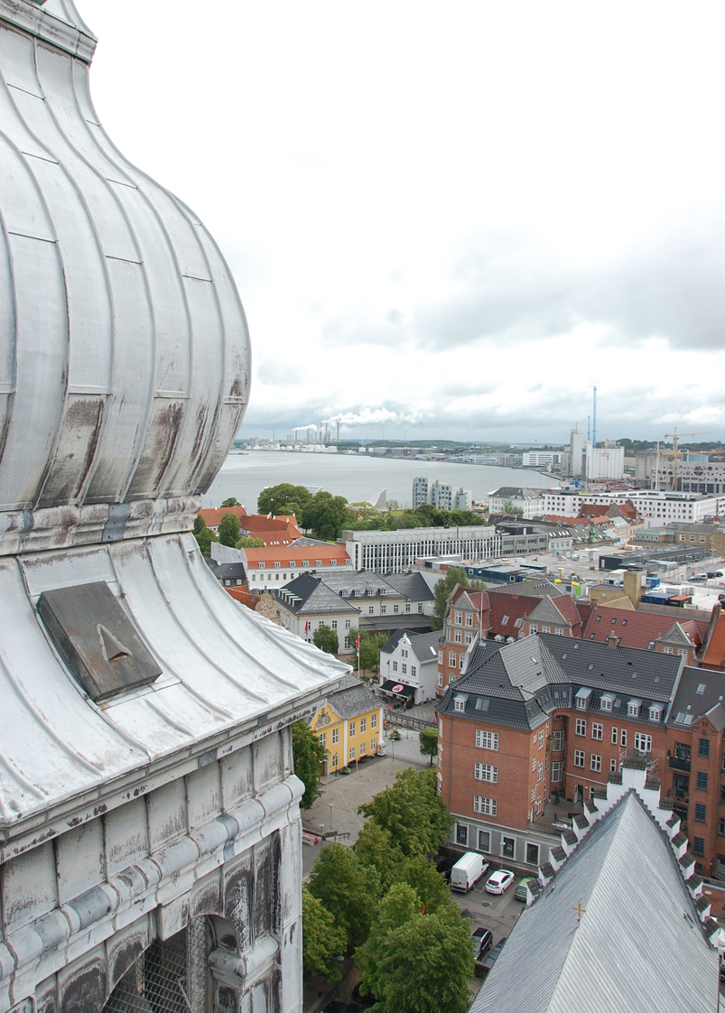 Byudsigt fra kirketårnets tag over havn og bygninger.