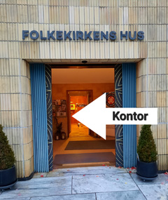 Gruppe samles på brostensbelagt torv uden for bygninger.