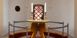 Moderne kirkealter med geometrisk lyskasse og høje lys.